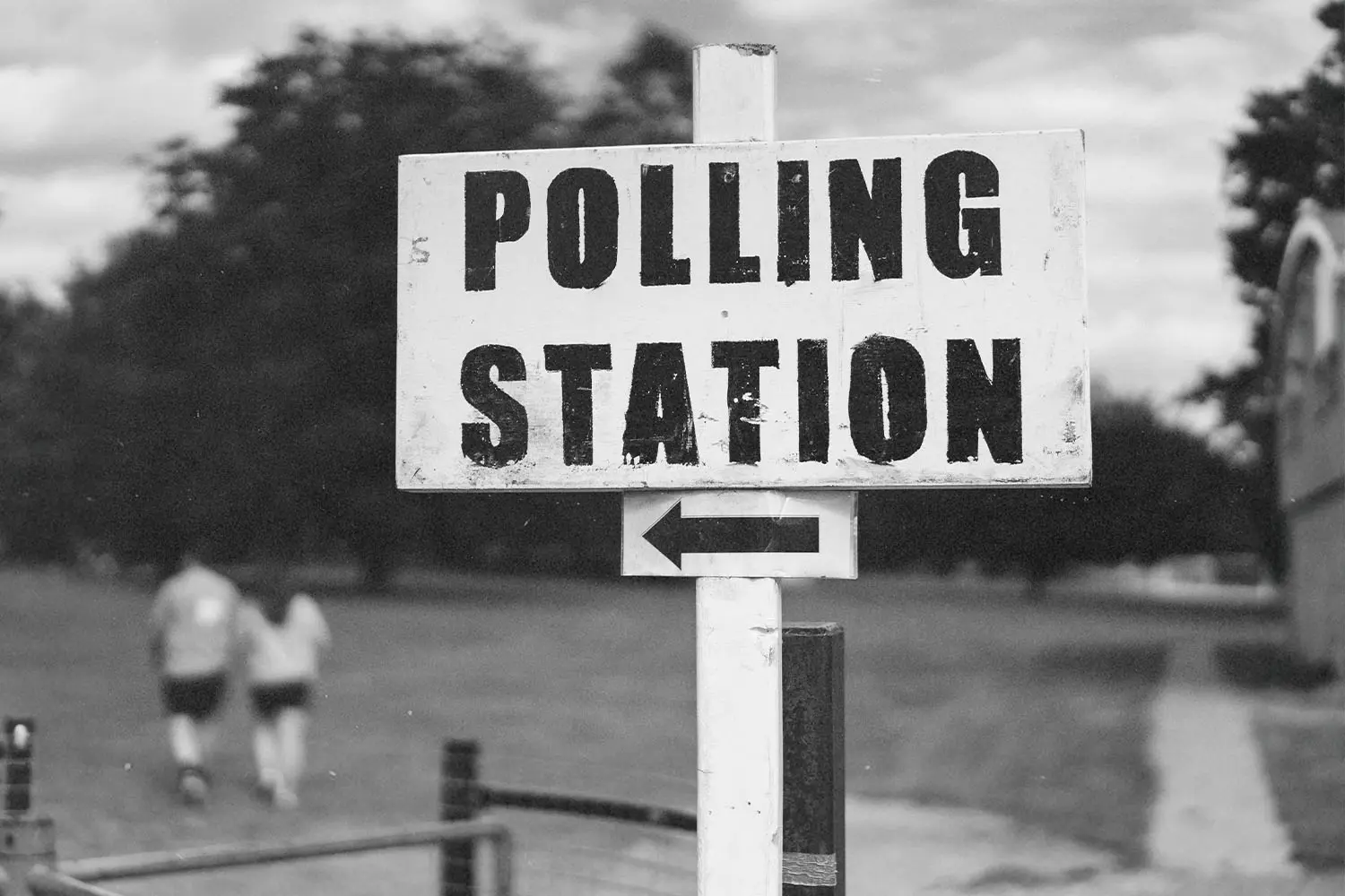 black and white photo of polling station sign with arrow pointing left