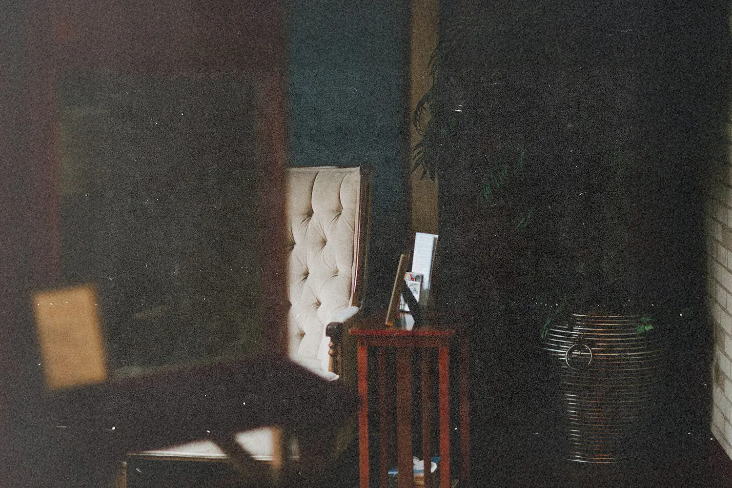A softly lit interior room with an upholstered chair, a small side table, and a tall plant creating a calm atmosphere