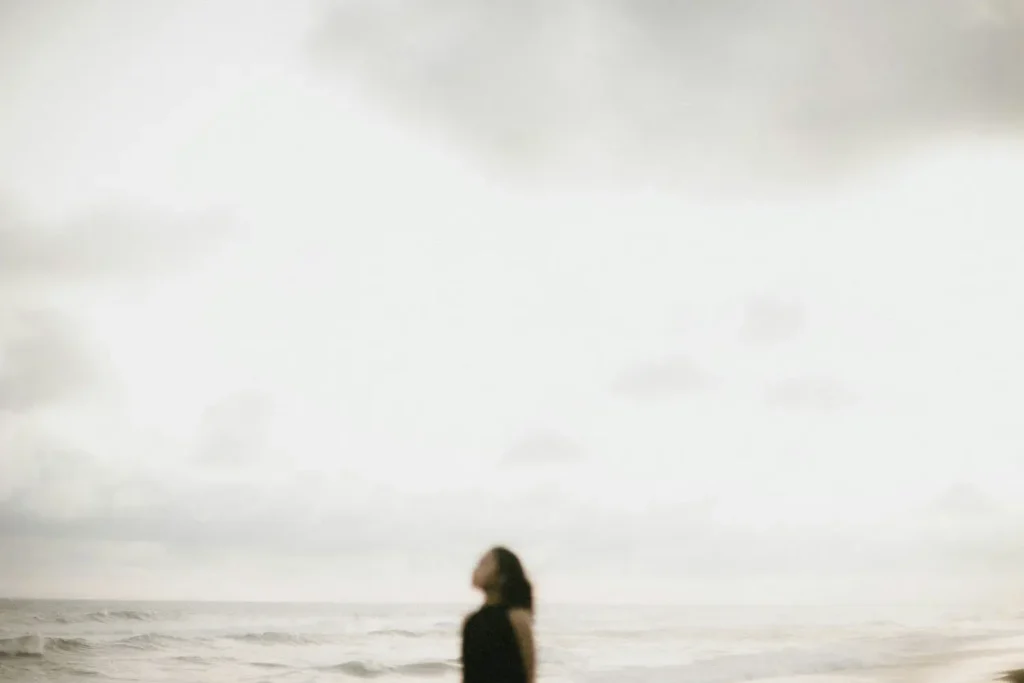 women on a beach looking up at a cloudy day