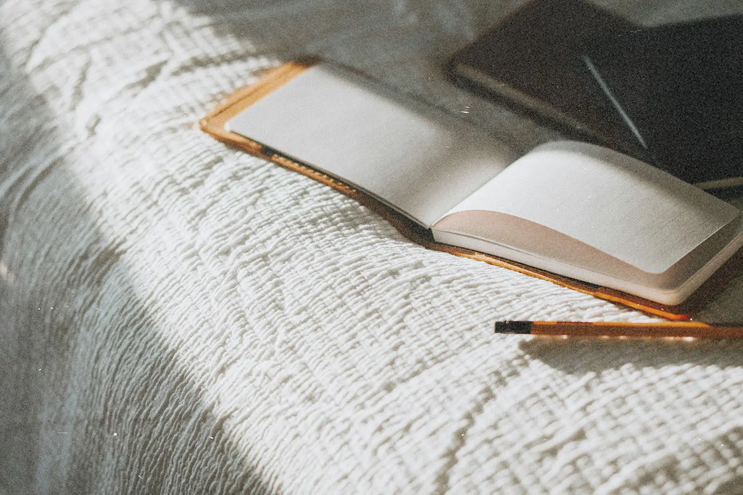 Open notebook resting on a textured blanket beside a pen in warm natural light