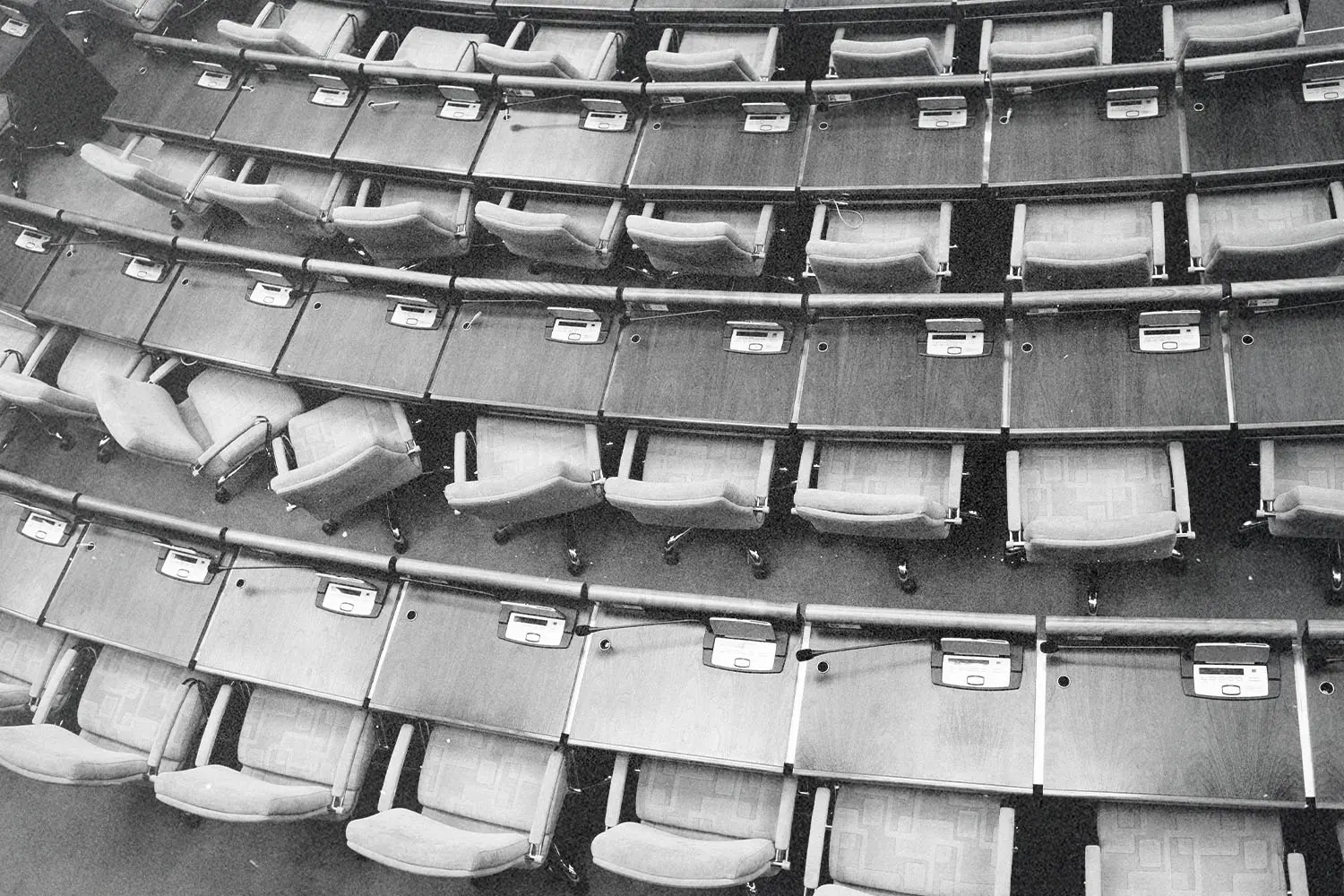 Rows of empty auditorium seats arranged in curved tiers with attached writing surfaces