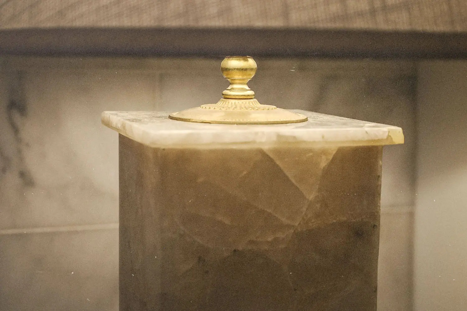 Marble column with an ornate gold finial on top in soft indoor lighting
