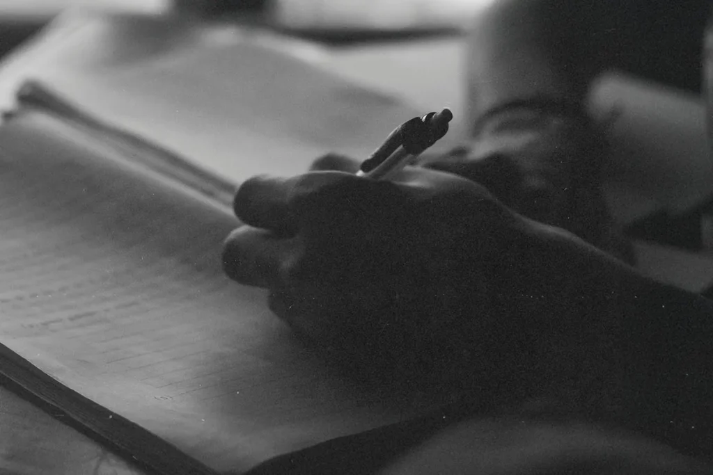 Close‑up of a hand writing in a notebook with soft lighting