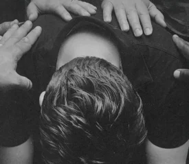 Laying hands in prayer on a man crouched over