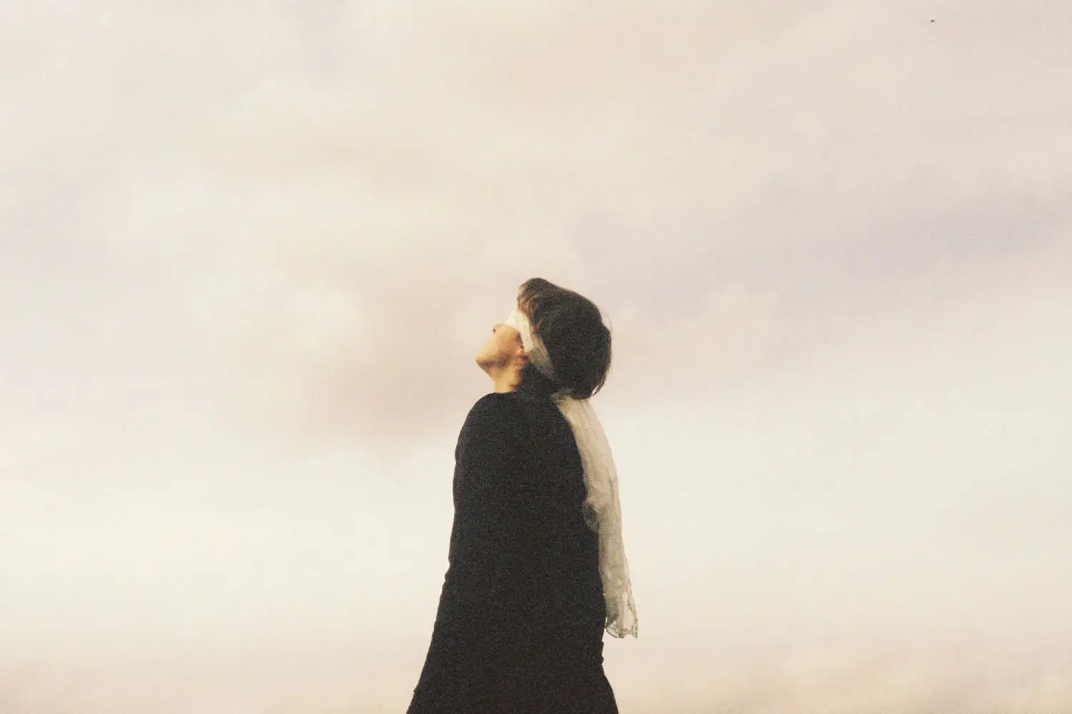 woman looking up with a cloudy background