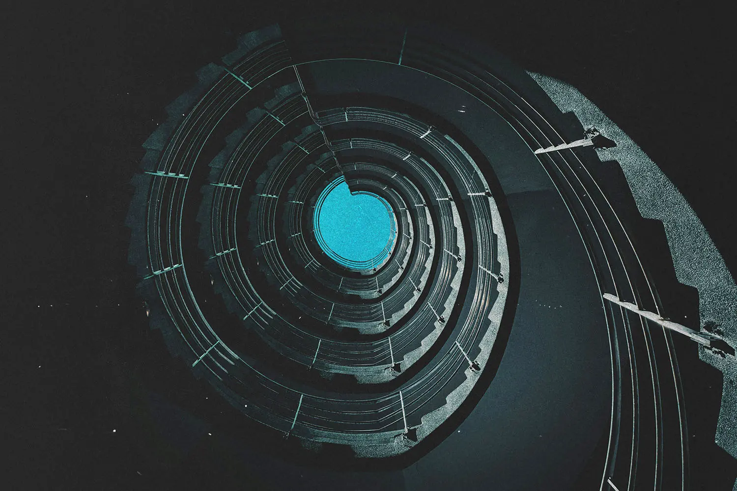 Circular view looking upward through a spiraling architectural structure toward a bright blue opening