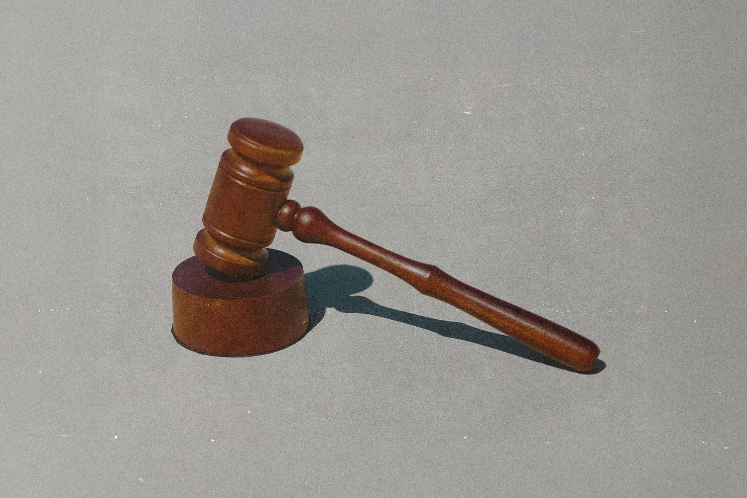 Courtroom gavel resting on a cream, neutral background