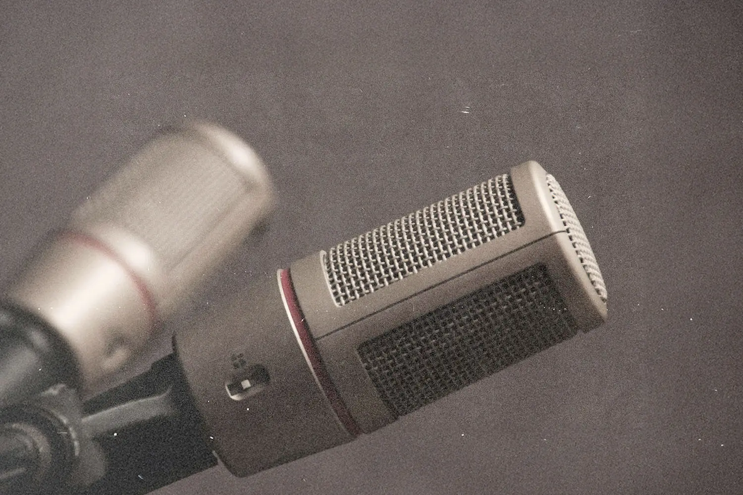 Two studio microphones positioned closely together against a neutral background