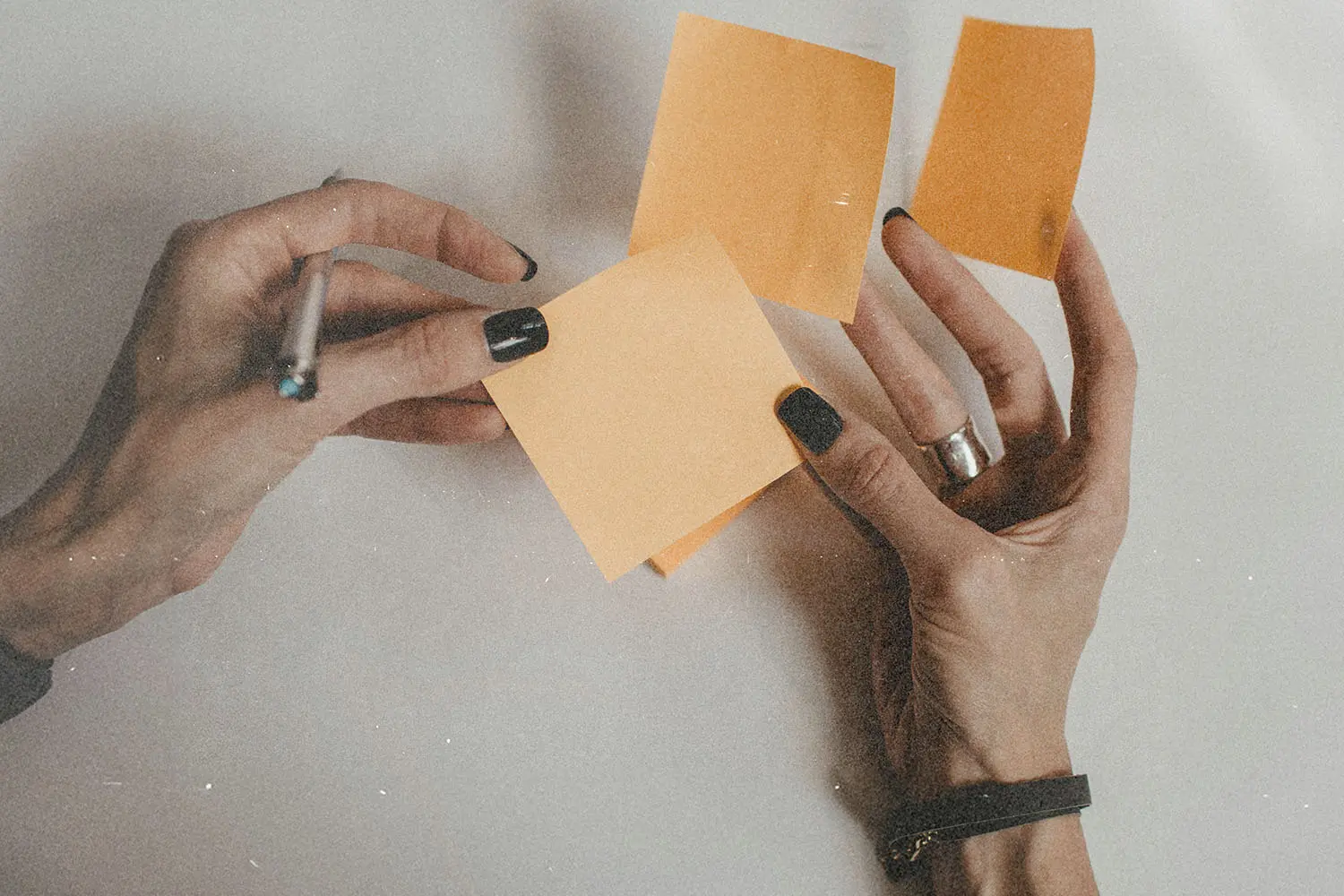 Hands holding and organizing orange sticky notes on a white surface