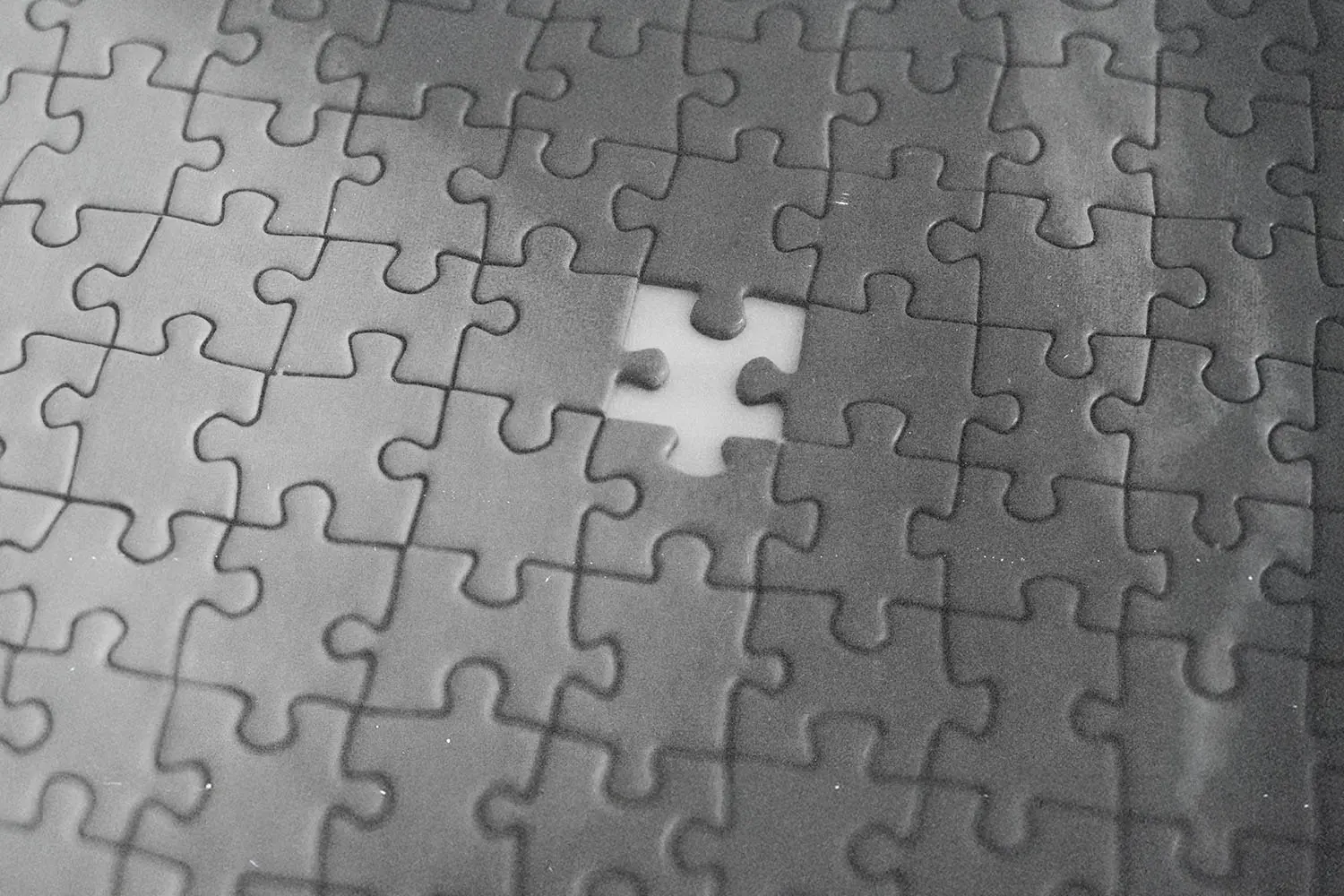 Black-and-white puzzle with one central piece missing, revealing an empty white space