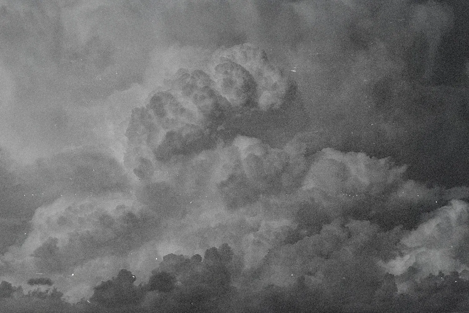 Dark, dramatic storm clouds forming dense shapes across a textured sky