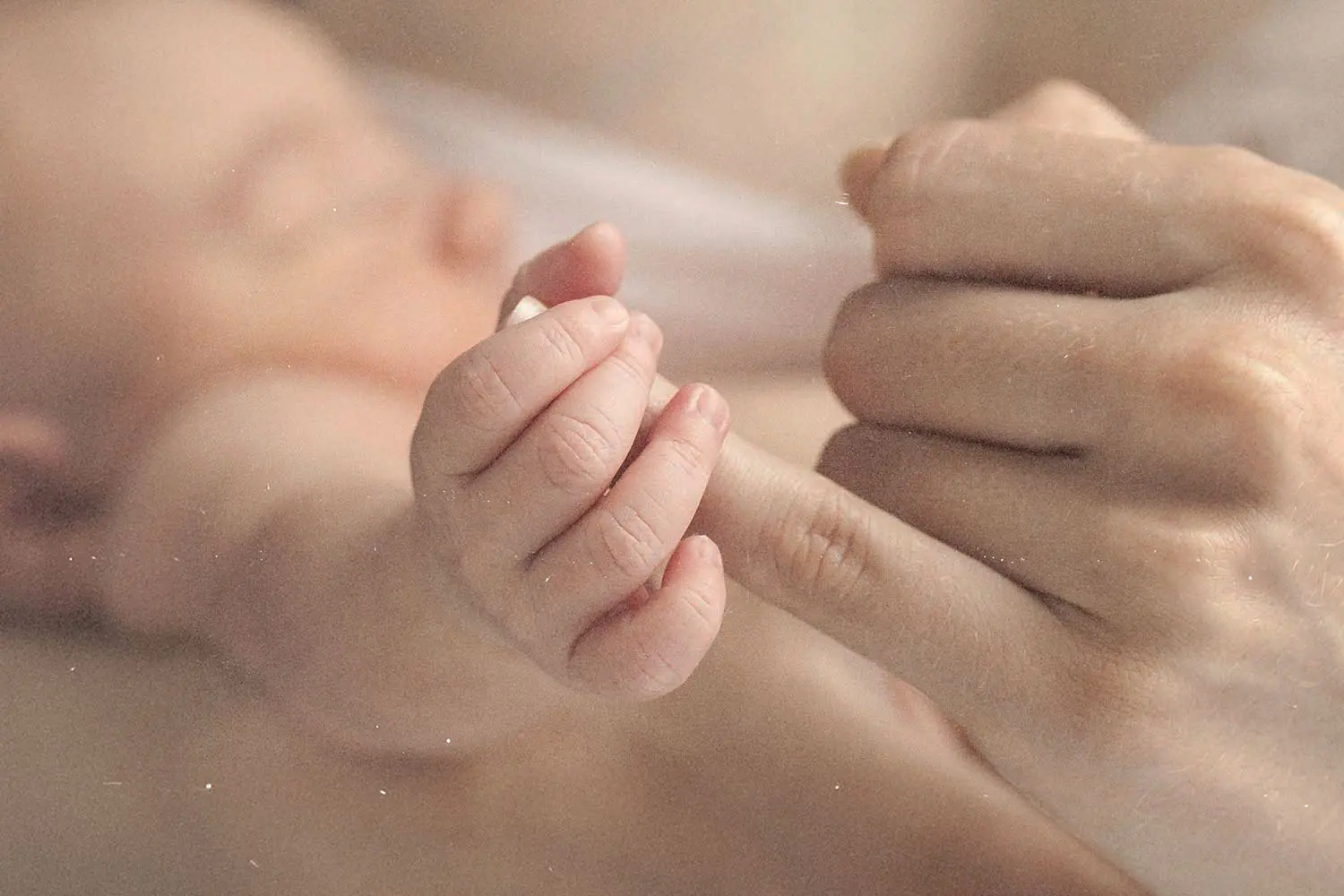 Close-up of a hand touching a ring on another person’s finger in soft, warm lighting
