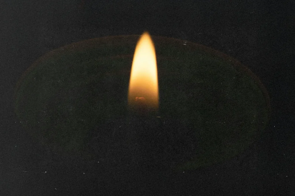 Single flame flickering in the dark, casting a soft glow