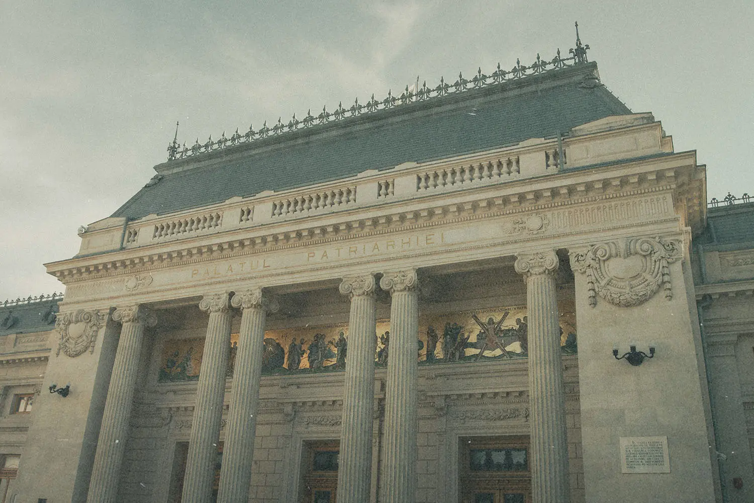 Historic building with tall columns, ornate carvings, and a large decorative frieze above the entrance