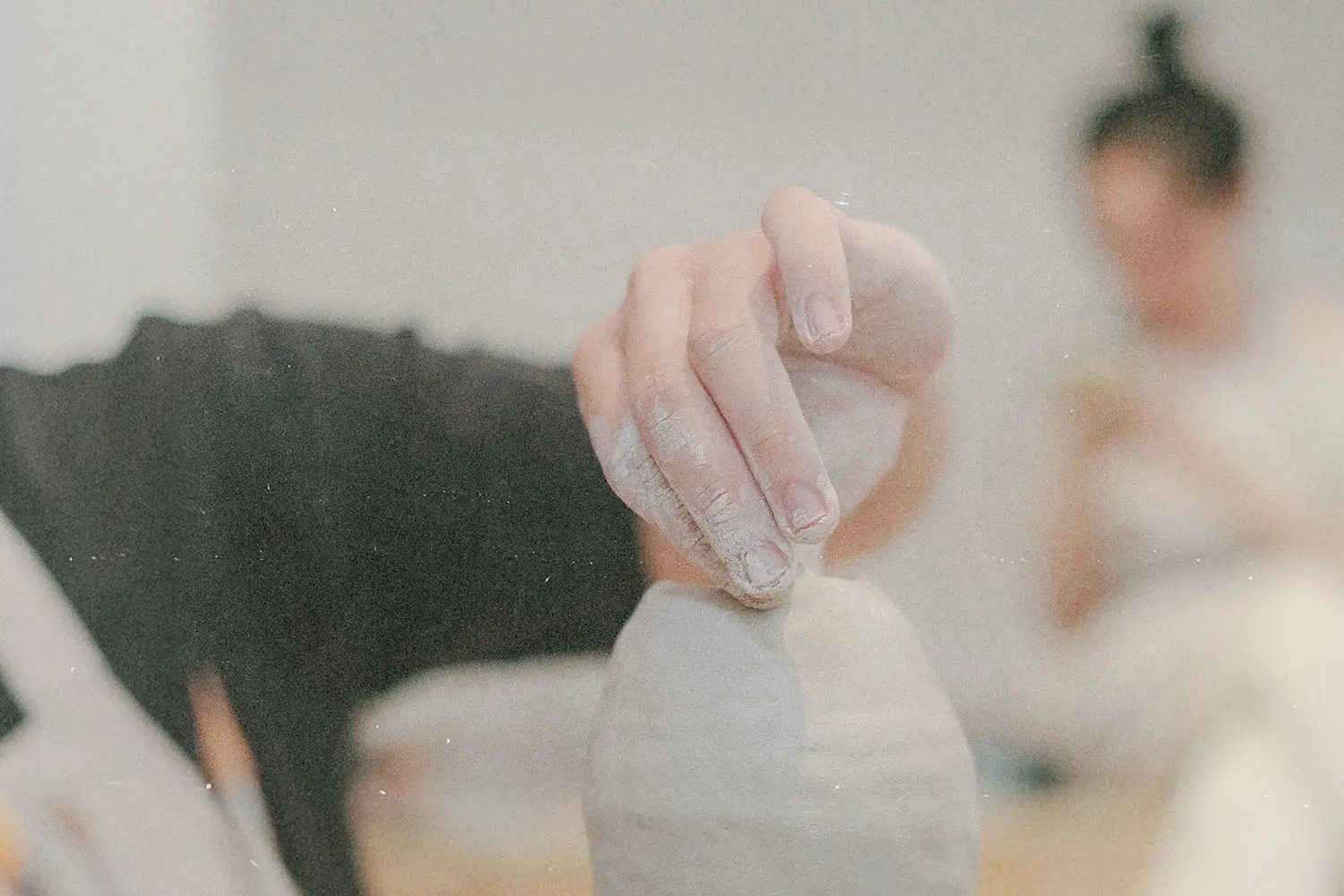 Close-up of a hand shaping a clay pot on a pottery wheel in a studio setting