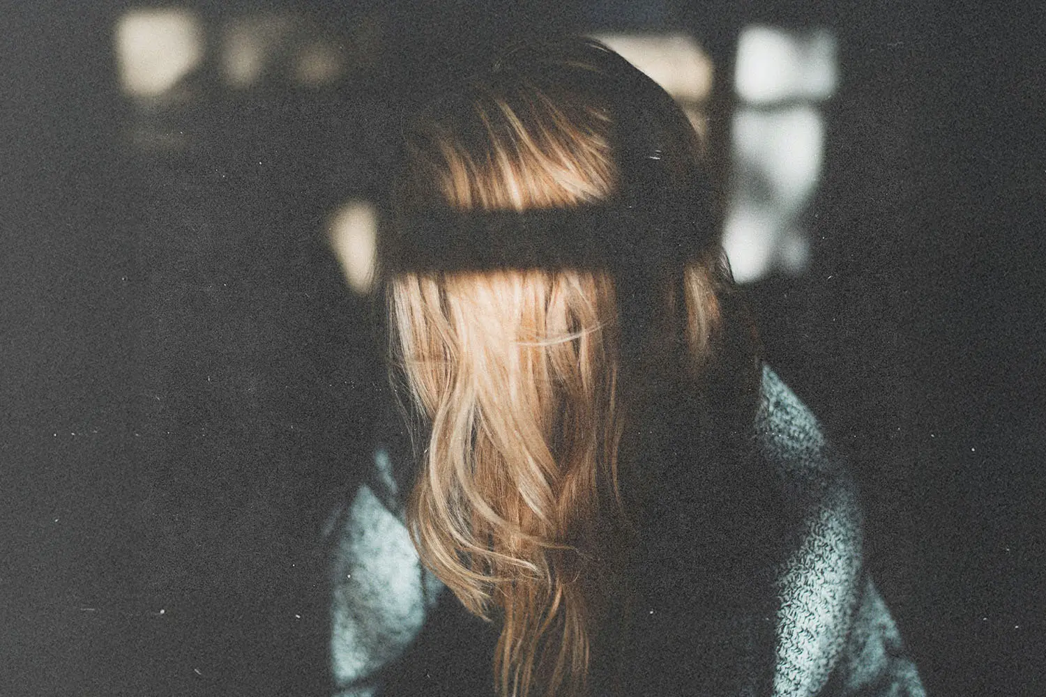 A person seated near a window with light and shadow cast across the scene.