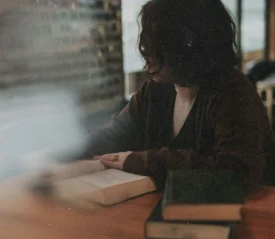 women reading a book at a wooden table