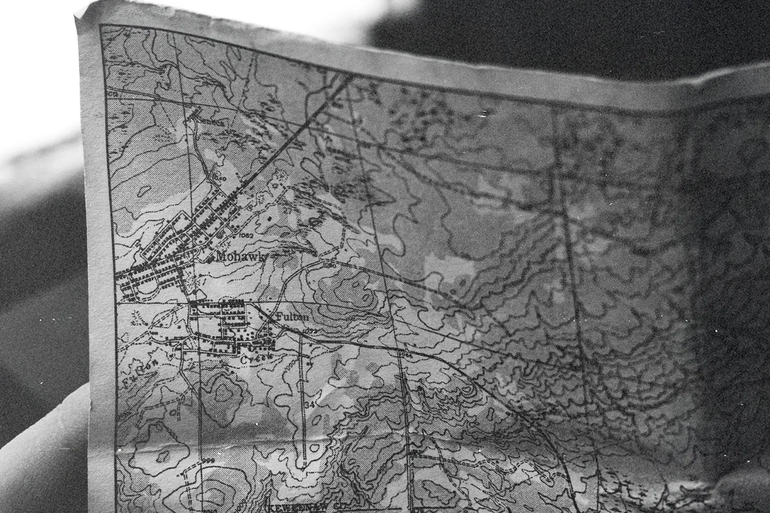 A folded paper map held open with roads and terrain visible.