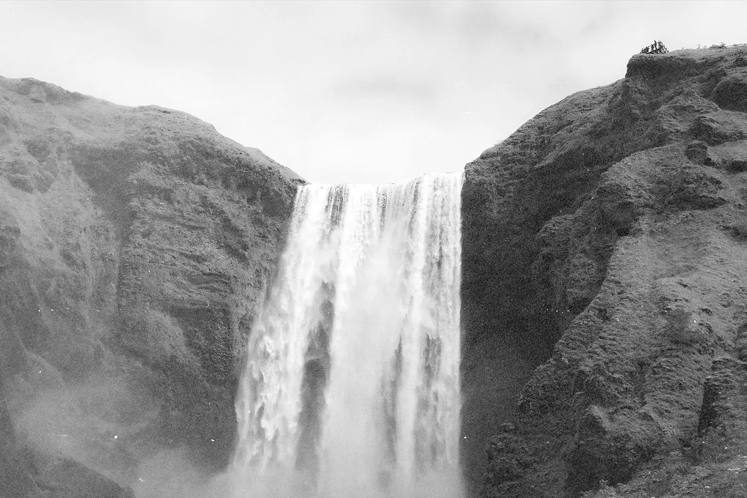A tall waterfall cascading between steep rock walls.