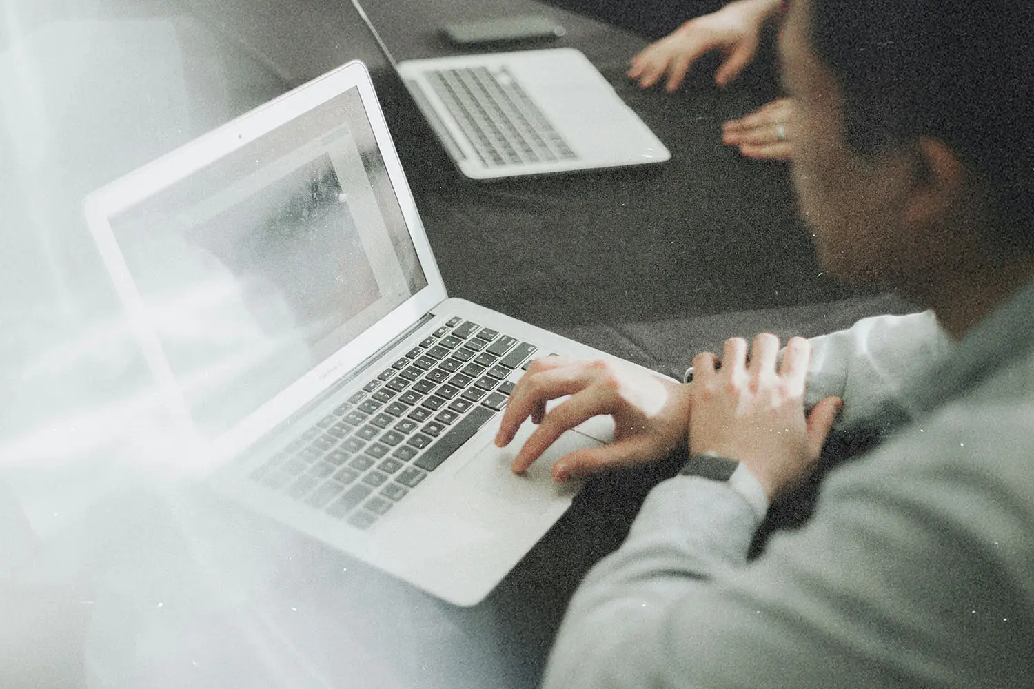 Two people working on laptops at a table.