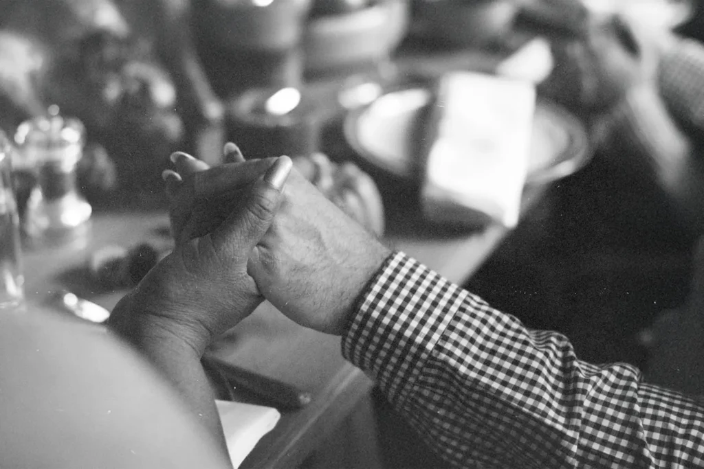 Two people hold hands across a table set with plates, bowls, and candles in a warm, intimate setting