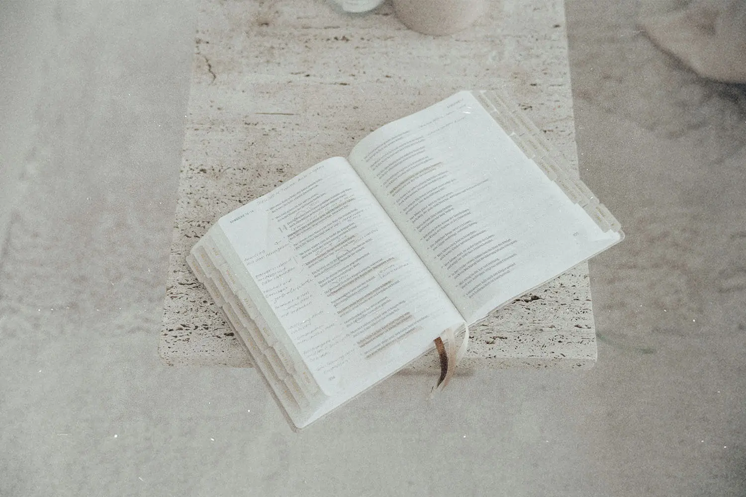 An open Bible resting on a stone or concrete surface with pages visible.