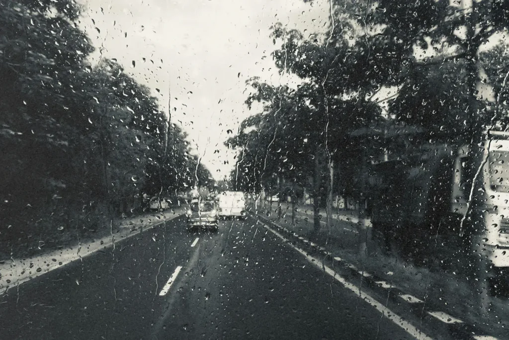 Raindrops on a clear window looking out to an open road