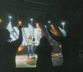 Worship band performing on stage with audience raising hands