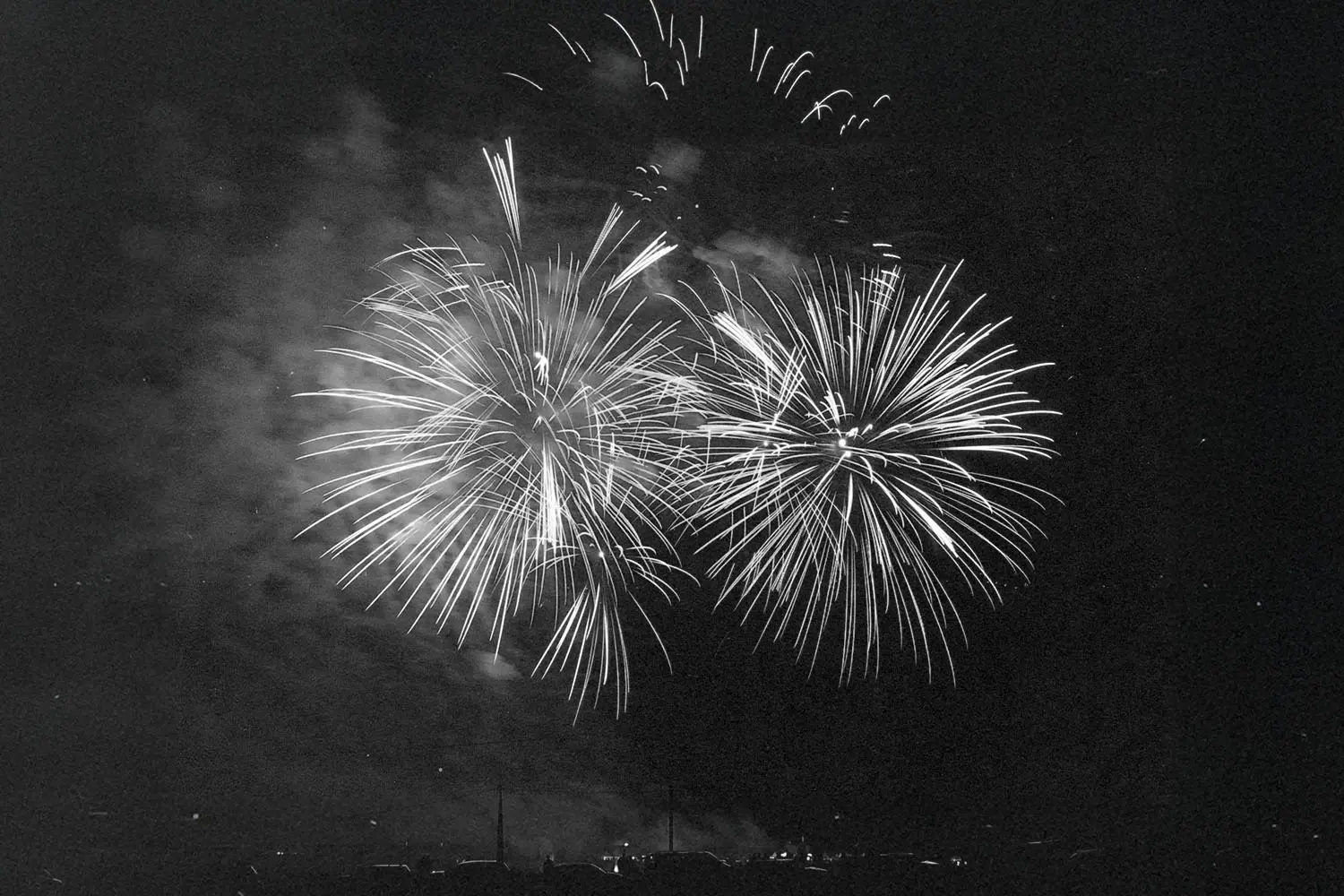 Black and white image of sky full of fireworks