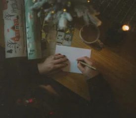 person writing a note next to wrapping paper
