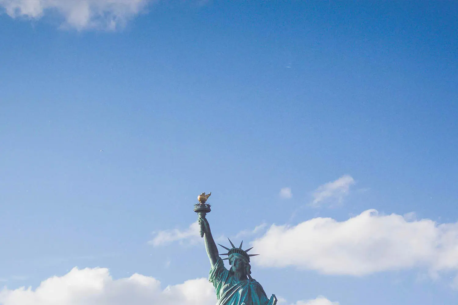 top of the statue of liberty and clouds in the sky
