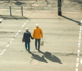 older couple holding hands walking across the street