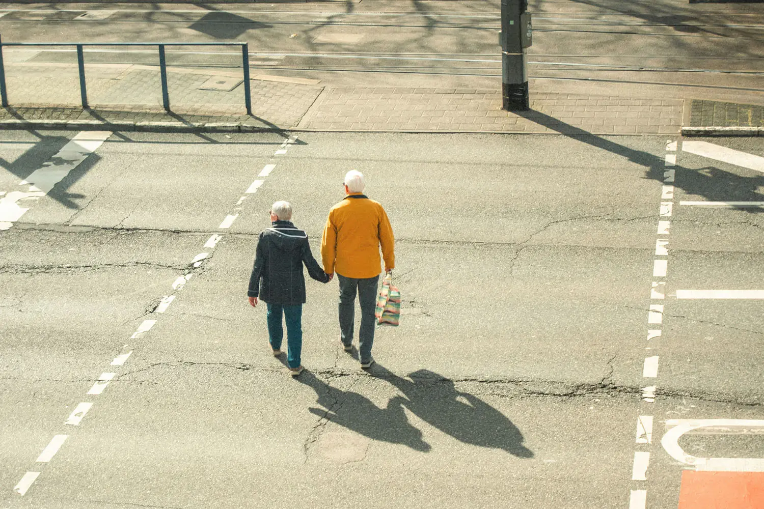 older couple holding hands walking across the street
