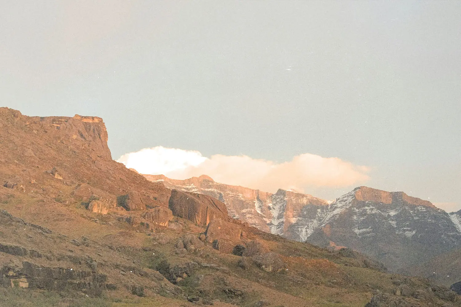 Rocky mountain landscape with snow-dusted peaks illuminated by soft early-morning light