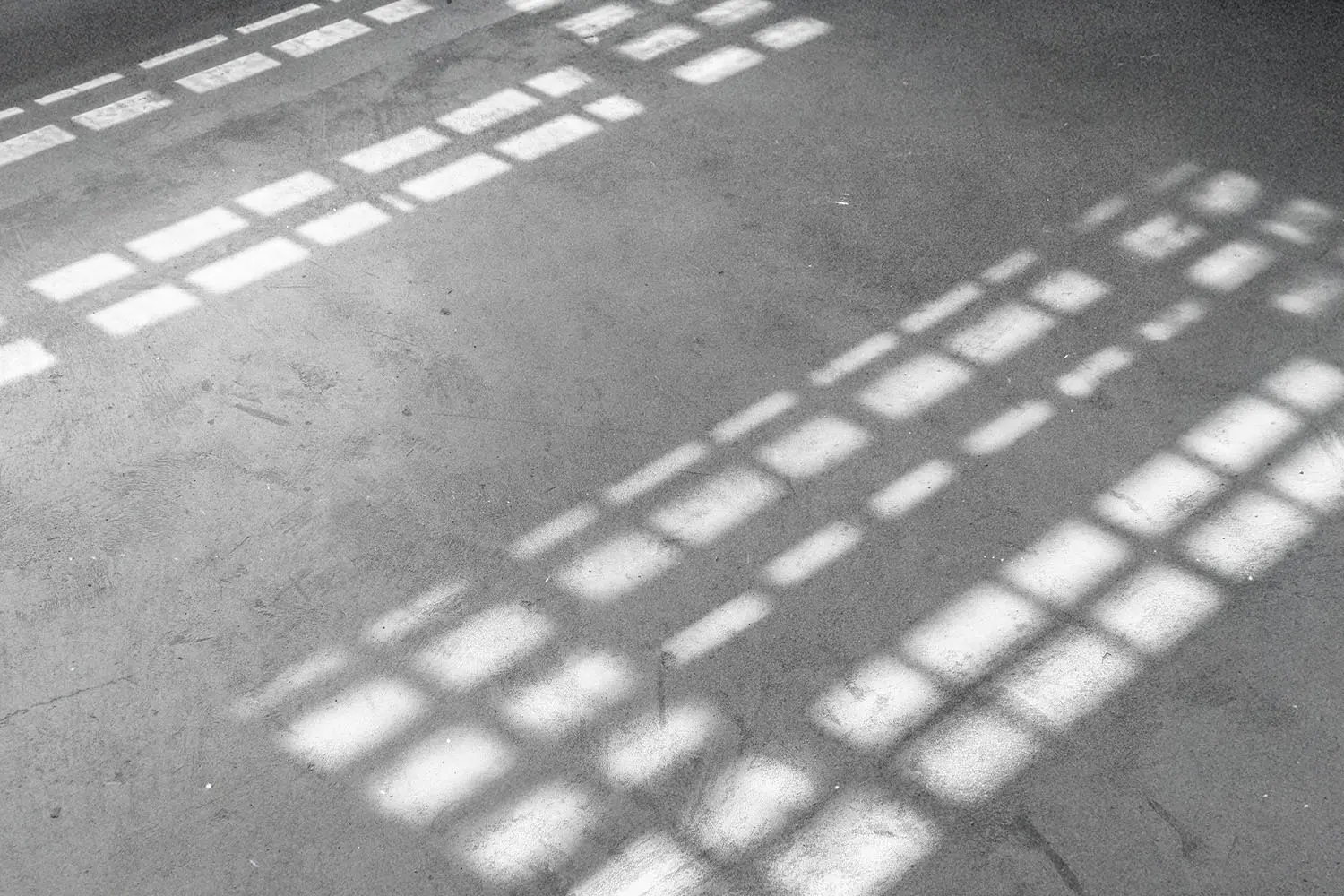 Bright rectangular patches of sunlight stream through a window, creating geometric patterns on a smooth floor