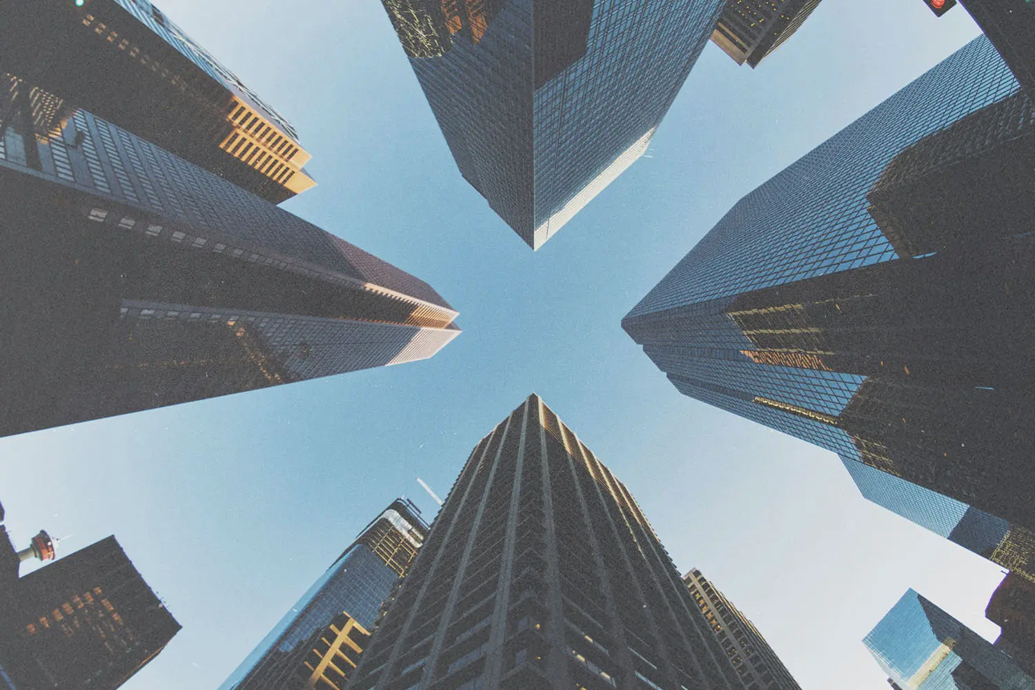 Upward view of tall skyscrapers forming a cross‑shaped opening toward the sky