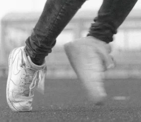 Close-up of a person in motion wearing worn sneakers on an outdoor track
