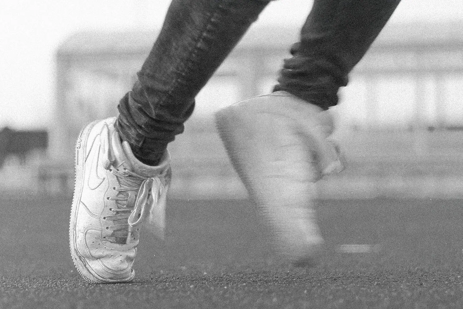 Close-up of a person in motion wearing worn sneakers on an outdoor track