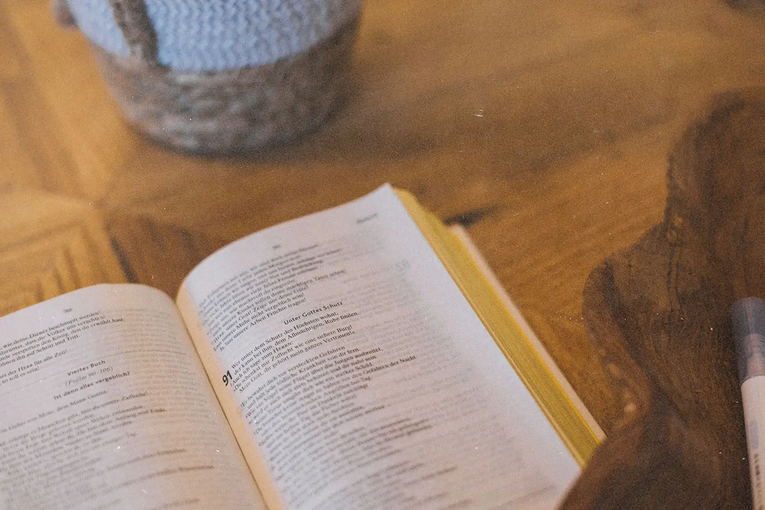 Open Bible laying on a wooden table with warm light and a woven basket in the background