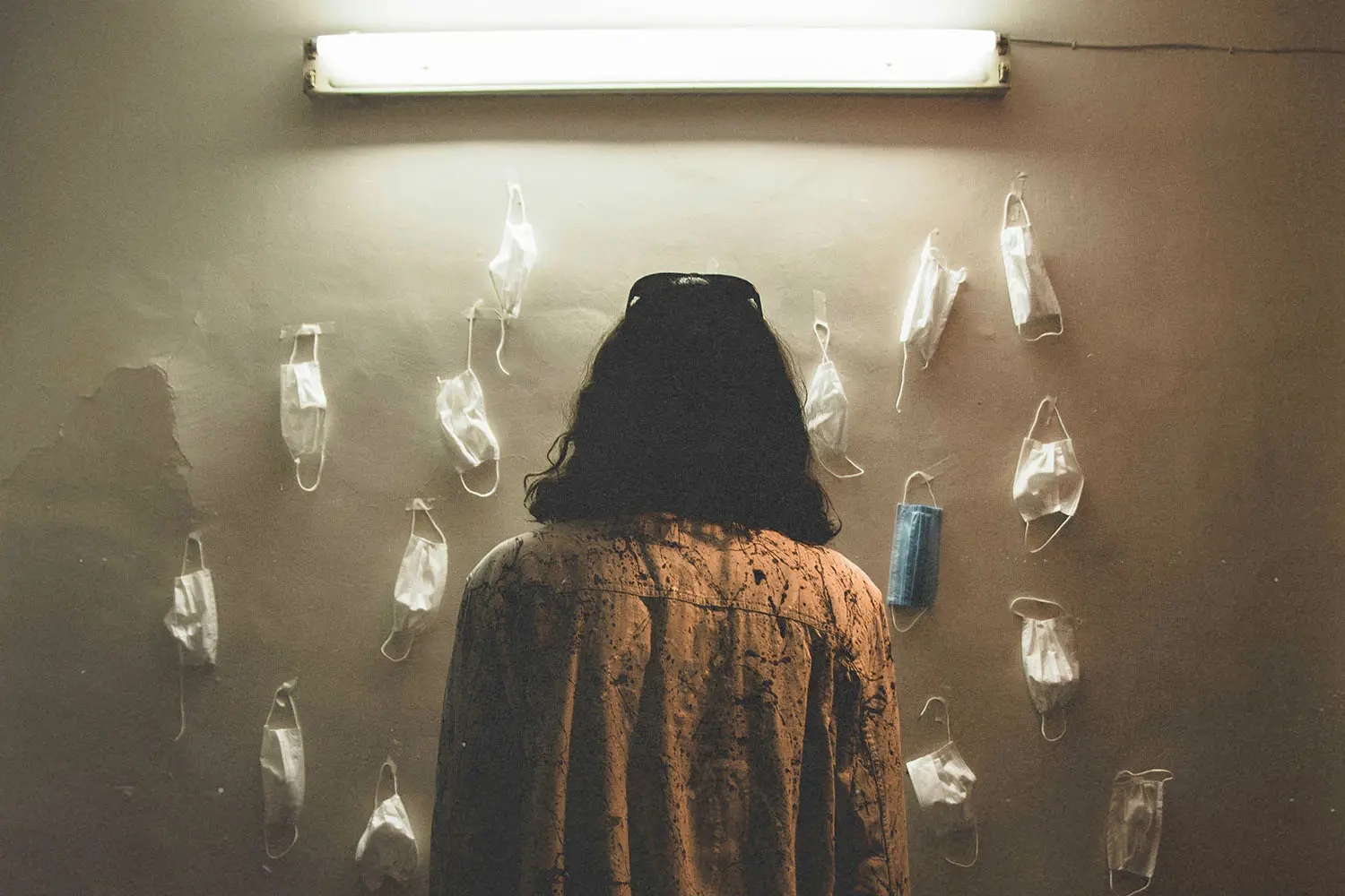 woman staring at a wall of tacked paper facemasks