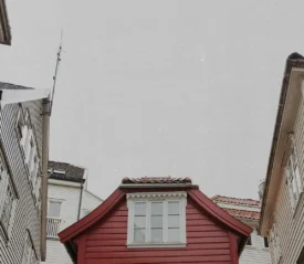 view of residential rooftops from the street with red home in the center