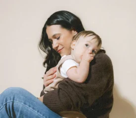 content young woman with dark hair holding a toddler