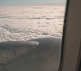 View of a bed of clouds and engine from an airplane window