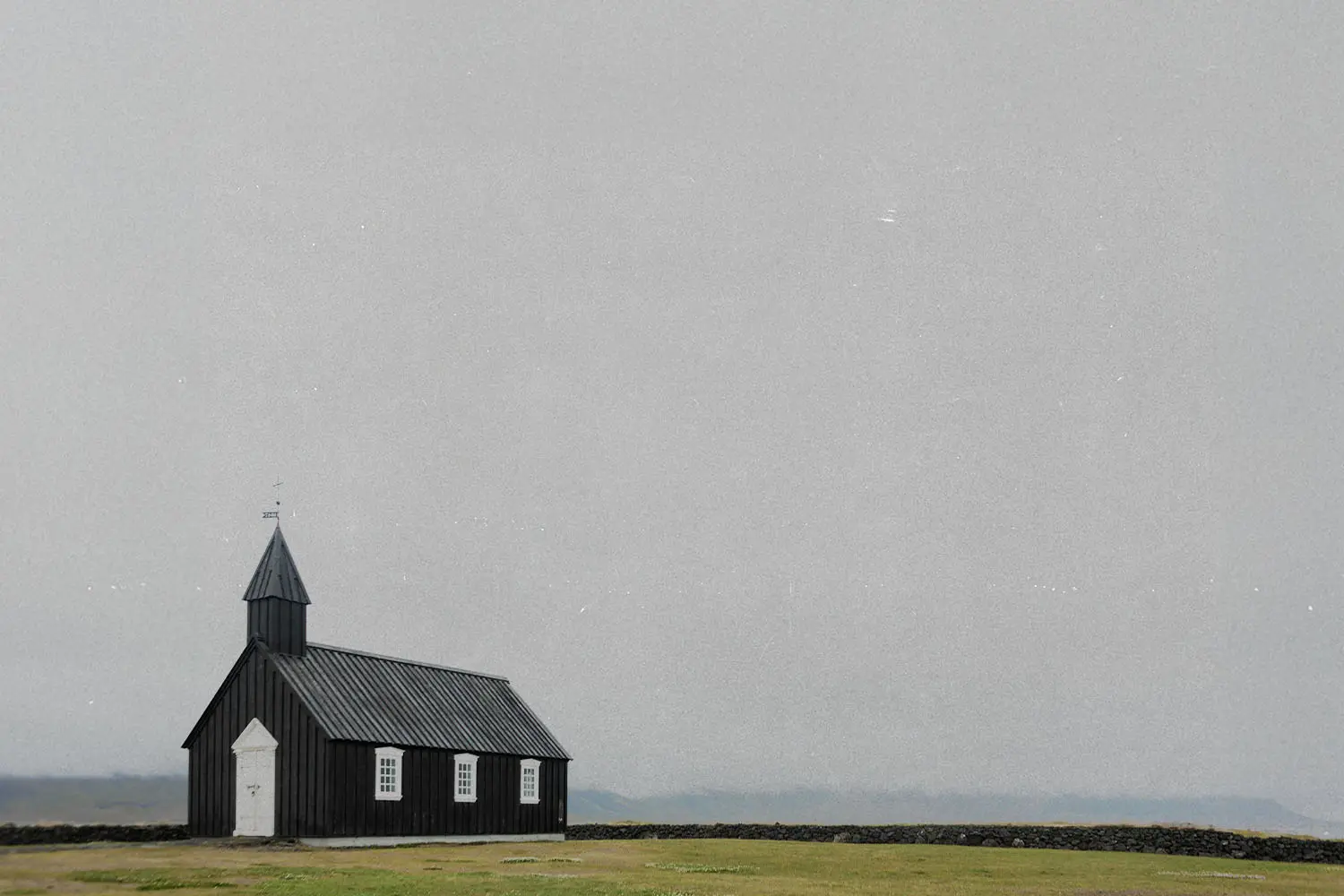 Rustic wooden church building in the distance of an open foggy field