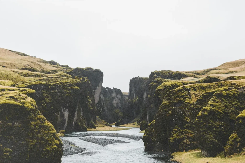 River winding through a steep moss-covered canyon under an overcast sky
