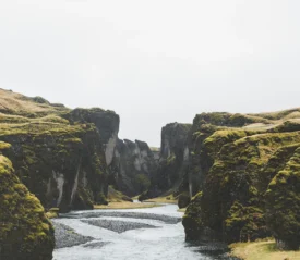 River winding through a steep moss-covered canyon under an overcast sky