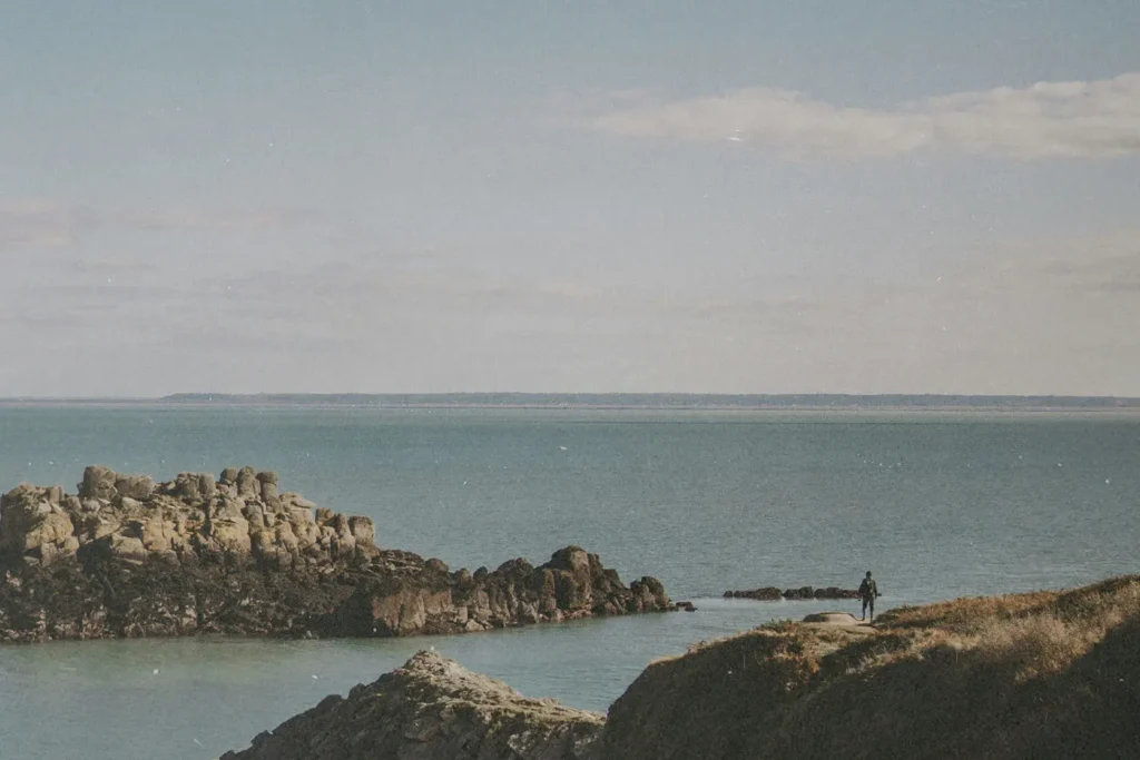 boulders coming up from a calm ocean