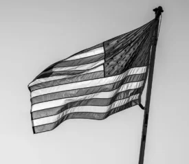 black and white photo of usa flag flying in breeze