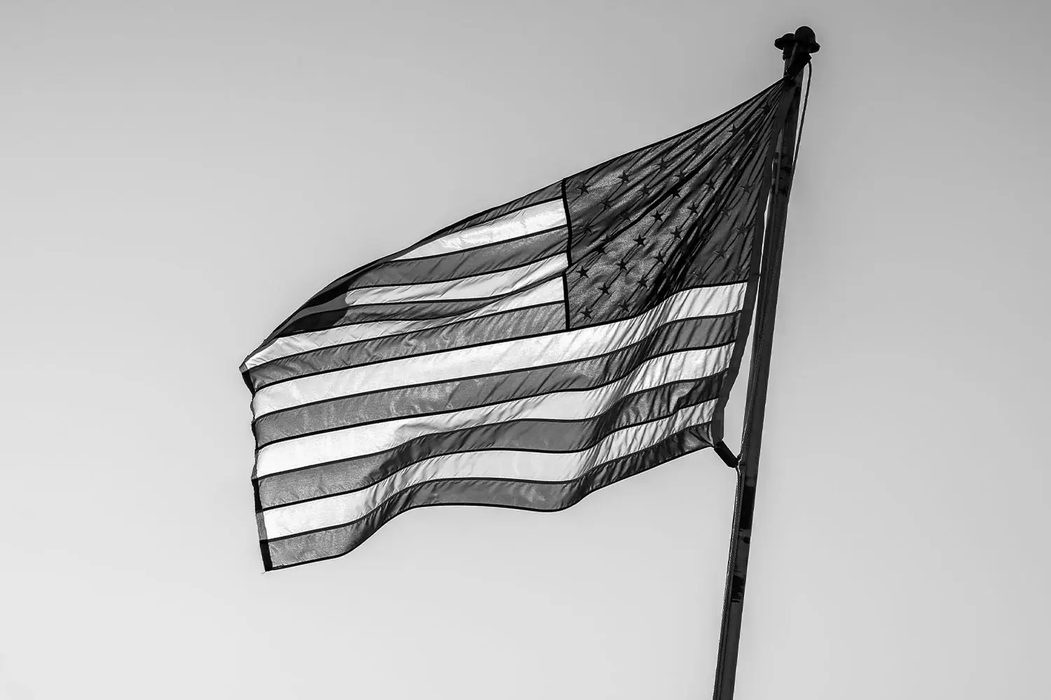 black and white photo of usa flag flying in breeze
