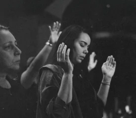 black and white photo of people with hands int he air praising